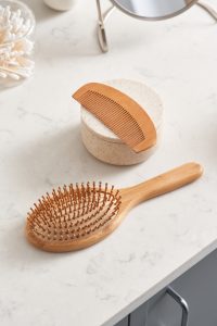 From above eco friendly bamboo combs and jar of natural cosmetic product placed on marble counter in clean bathroom